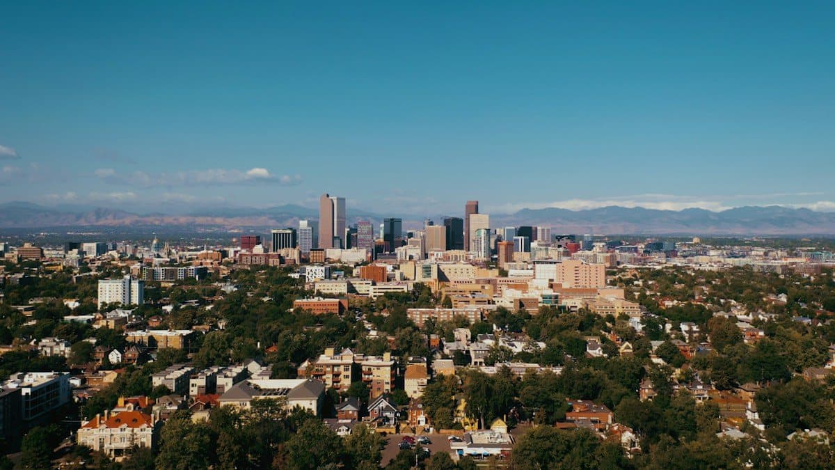 Denver skyline rising above residential neighborhoods with mountains in the distance