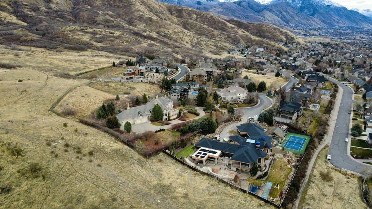Aerial view of luxury homes on a hillside below snow-capped mountains